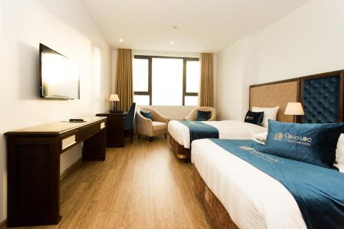 Una habitación de hotel con dos camas y un escritorio. en Song Loc Luxury Hotel, en Ha Long
