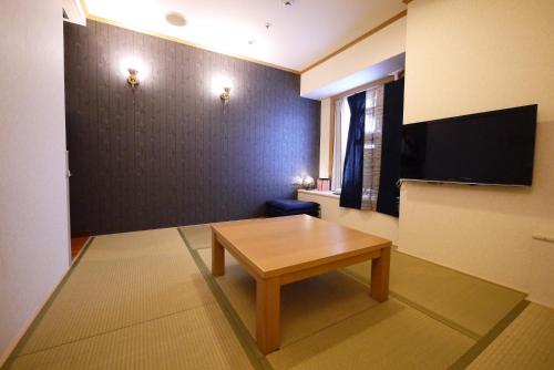 a living room with a table and a flat screen tv at U-Community Hotel in Osaka