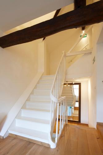 a white staircase in a house with wooden floors at B&B Hof van Vervoering in Voeren
