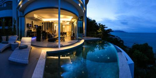 a house with a swimming pool in front of the ocean at Villa Callisto in Thong Son Beach