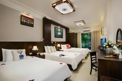 Habitación de hotel con 3 camas, mesa y sillas en Hanoi Stella Hotel en Hanói