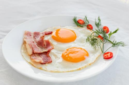 un piatto di uova e pancetta su un piatto bianco di Hanoi Stella Hotel a Hanoi
