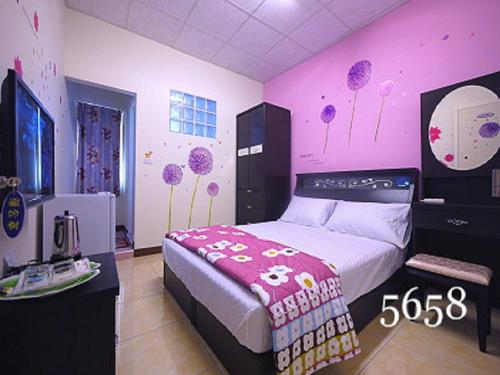 a bedroom with a bed with a pink wall at Hua Qiao De Jia in Donggang