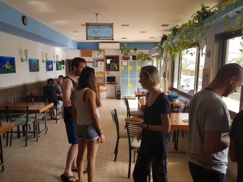 a group of people standing in a restaurant at Arava Hostel in Eilat