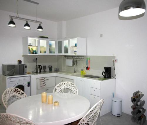 a white kitchen with a white table and chairs at Pereybere Cosy in Pereybere