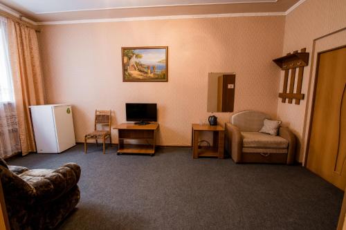 a living room with a couch a chair and a refrigerator at Tri Peskarya Hotel in Kursk