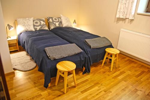 a large bed with blue sheets in a room with two stools at Apartament na Starym Dworcu in Goczałkowice-Zdrój