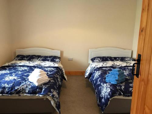 a bedroom with two beds with blue and white sheets at High Road Cottage in Achill