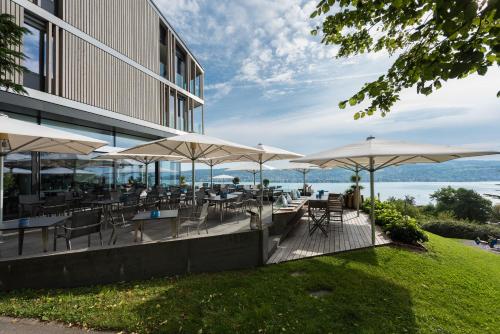ein Restaurant mit Tischen, Stühlen und Sonnenschirmen in der Unterkunft Belvoir Swiss Quality Hotel in Rüschlikon