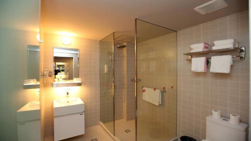 a bathroom with a shower and a sink and a toilet at Jinjiang Inn Tianjin Haitai Industrial Parks in Tianjin