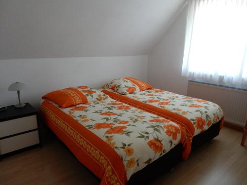 a bedroom with a bed with a flowered blanket and a window at Vechtetal-Garten in Laar