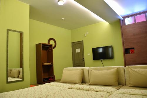 ein Wohnzimmer mit einem Sofa und einem Flachbild-TV in der Unterkunft Red Roof B&B in Taitung