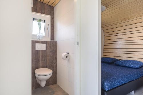 a small bathroom with a bed and a toilet at Luxe Tiny House in Stroe