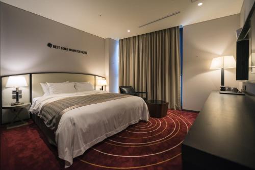 a hotel room with a bed and a desk at Best Louis Hamilton Hotel Changwon in Changwon