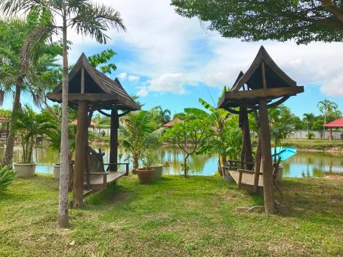 a group of gazebos next to a body of water at Khwanruen Fishing Resort in Ban Chang