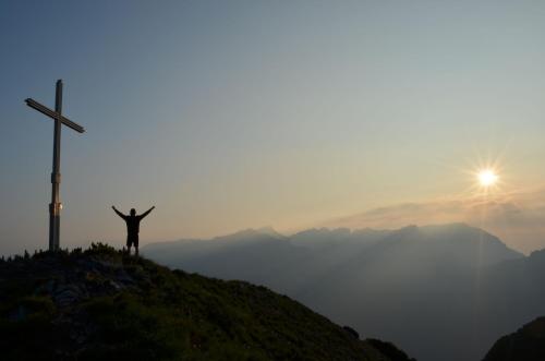 a man standing on top of a hill next to a cross at Landhaus Obertuschenhof in Pertisau