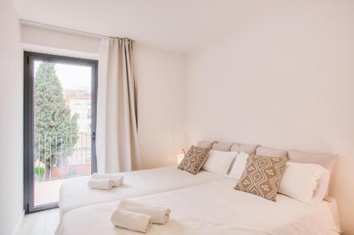 a bedroom with two beds and a large window at Flateli - Plaça Catalunya 42 in Girona