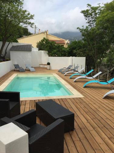 una piscina en una terraza de madera con sillas alrededor en Camping les Orangers en San-Martino-di-Lota