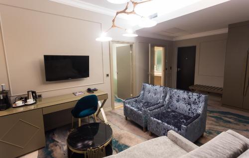 a living room with a couch and a desk with a television at Aqva Hotel & Spa in Rakvere