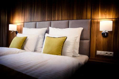 Habitación de hotel con cama con sábanas blancas y almohadas amarillas. en Ruben Hotel Zielona Góra, en Zielona Góra