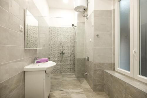 a white bathroom with a sink and a shower at Downtown Rijeka in Rijeka