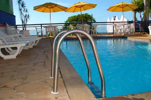 伊里里的住宿－達麥美亞賓館，一个带遮阳伞和椅子的游泳池以及游泳池