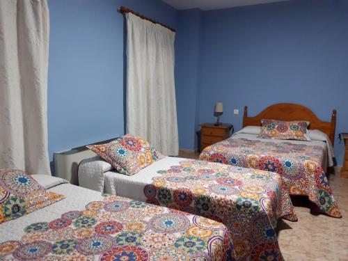 - une chambre avec 2 lits et des murs bleus dans l'établissement Hostal Julio, à Trujillo