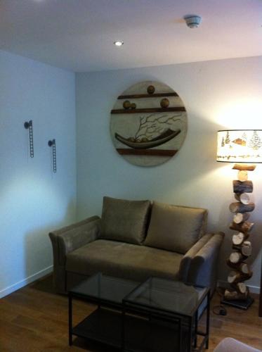 a living room with a couch and a clock on the wall at Hotel de la Lande in Le Brassus