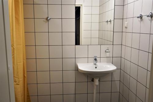 een wit betegelde badkamer met een wastafel en een spiegel bij Downtown Hostel in Tartu