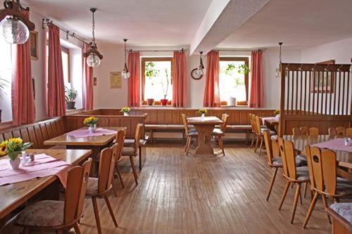 Gasthof zur Krone في Burghaslach: مطعم بطاولات وكراسي خشبية وستائر حمراء