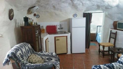 a living room with a refrigerator and a kitchen at Cueva Rural La Noguera in Pegalajar