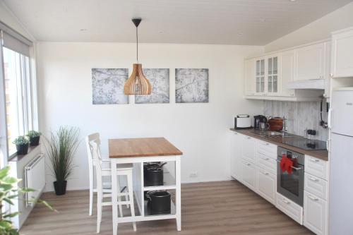 a kitchen with white cabinets and a wooden table at Lynghagi House in Vegamót