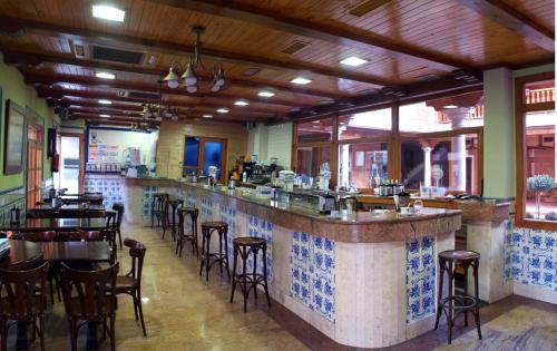 a restaurant with a bar with stools at Hotel Menano in Manzanares