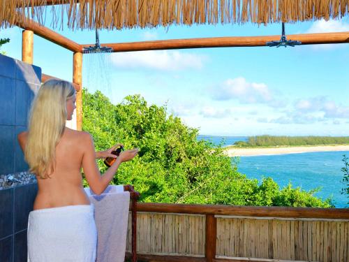 a woman standing on a balcony looking out at the ocean at Machangulo Beach Lodge in Santa Maria