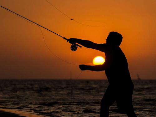 a man fishing on the beach at sunset at Machangulo Beach Lodge in Santa Maria