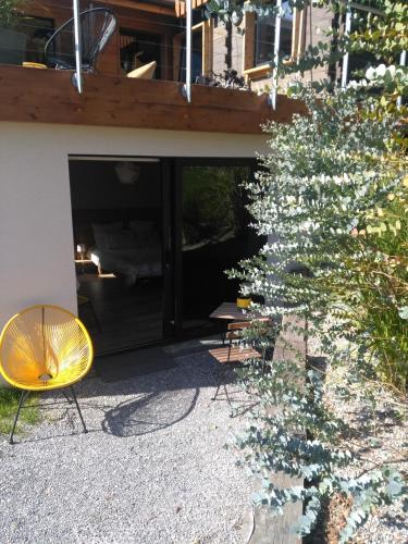 ein gelber Stuhl und ein Baum vor einem Gebäude in der Unterkunft Le chalet du Lac in Doussard