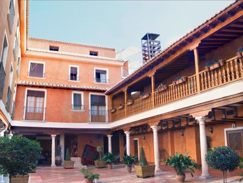 an apartment building with a balcony and plants at Hotel Menano in Manzanares