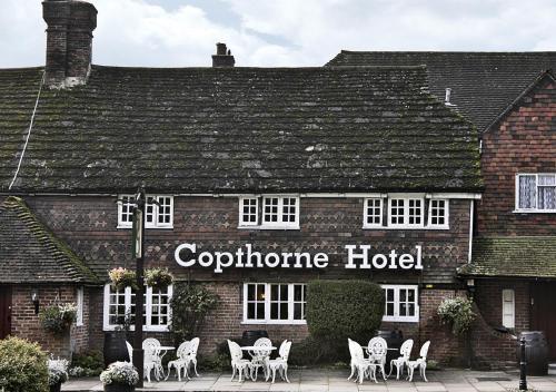 a hotel with white chairs in front of a building at Copthorne Hotel London Gatwick in Crawley