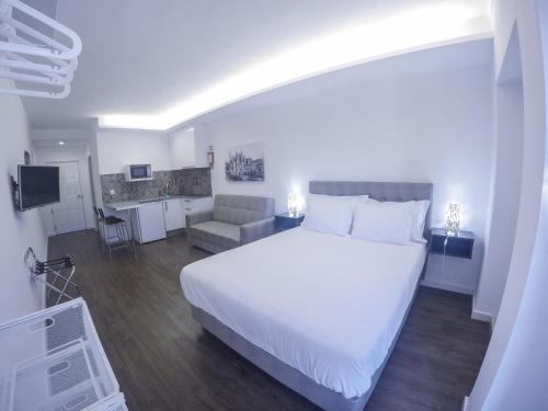 a bedroom with a large white bed and a kitchen at Mosteiro View in Batalha