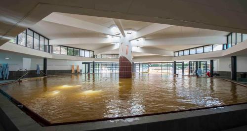 een groot zwembad met water in een groot gebouw bij Residence Cybele "Grand Confort" in Brides-les-Bains