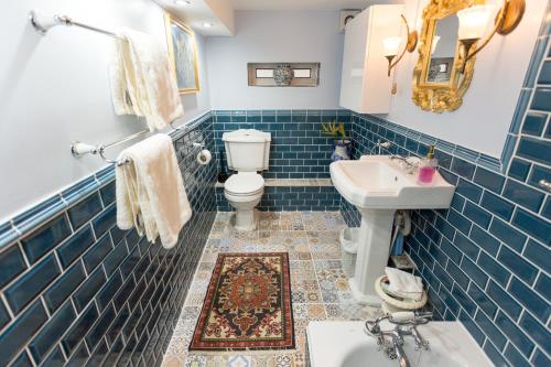 a blue tiled bathroom with a toilet and a sink at The Ascott in Manchester