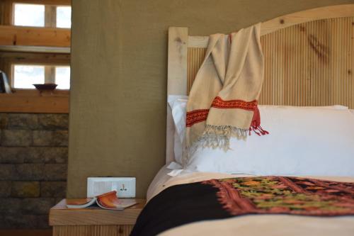a bedroom with a bed with a wooden head board at Kudrat - A Boutique Homestay- Tirthan Valley in Banjār