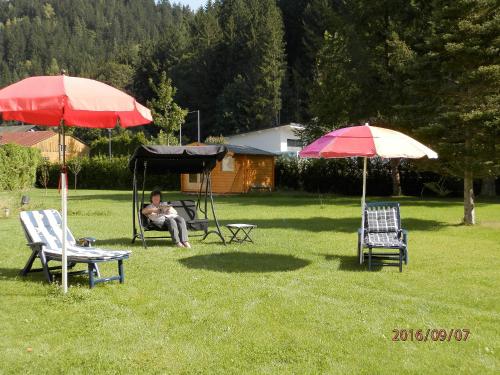 a person sitting in a chair under two umbrellas at Ferienwohnungen Haus Waltraud in Steinwiesen