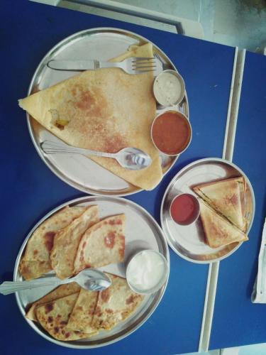 ein Tisch mit Tellern voller Pizza und Getränken in der Unterkunft Hotel Ramnivas in Udaipur