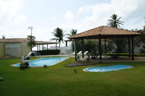 a resort with a pool and a gazebo at Pousada Corais de Maracajaú in Maracajaú