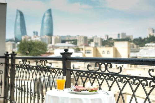 una mesa con un plato de comida y una bebida en el balcón en Old City Inn Hotel en Bakú