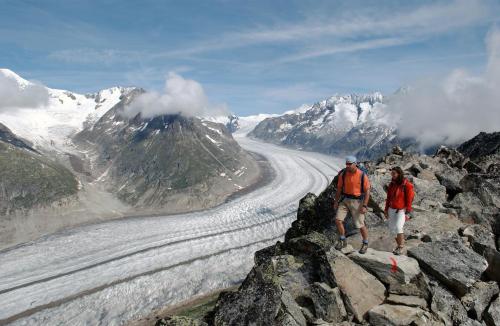 two people standing on top of a mountain with a glacier at Badehotel Salina Maris – Wellness & Vintage in Mörel