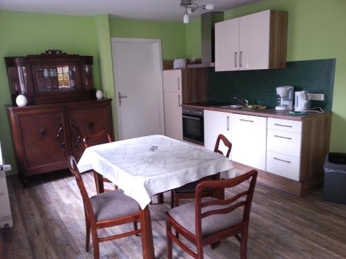a kitchen with a table and chairs and a kitchen with green walls at Ferienwohnungen "Altes Bachhaus" in Eisenach