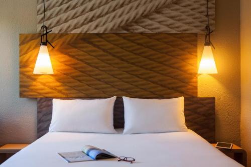 a bed with a pair of glasses and a book on it at ibis Velizy Jouy-En-Josas in Jouy-en-Josas