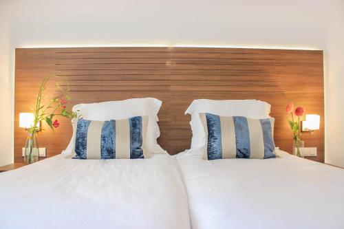 a bedroom with two white beds and a wooden headboard at A-Hotel Oosterhout in Oosterhout